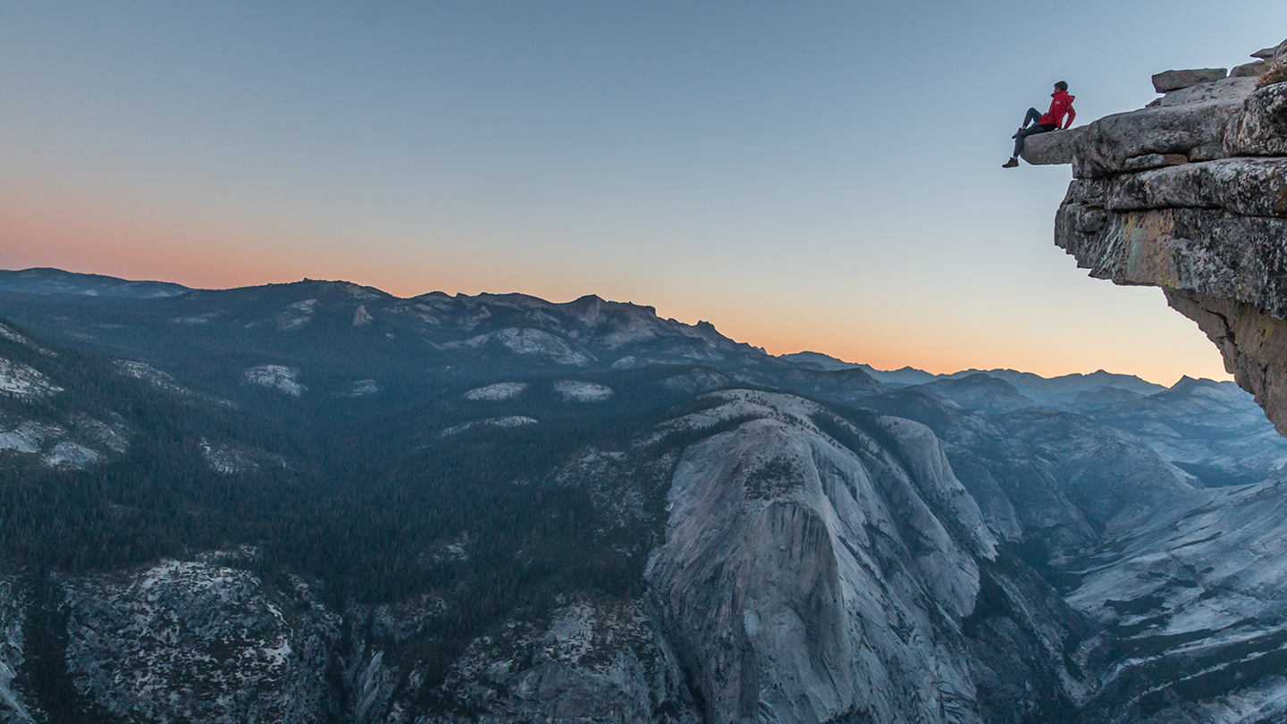 Woman sitting on edge of mountain