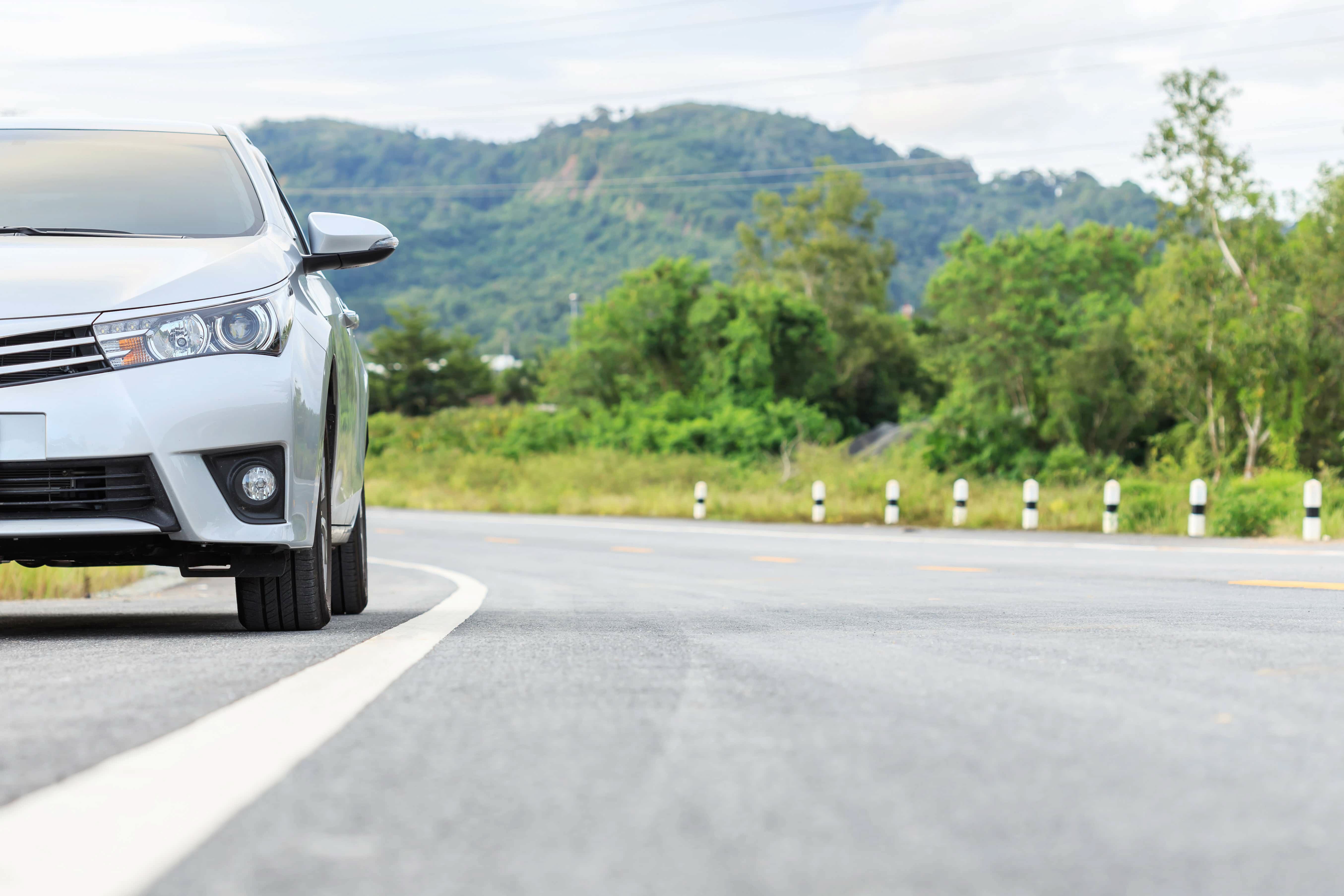 Passenger Car Driving on Road with Mountain in the Background