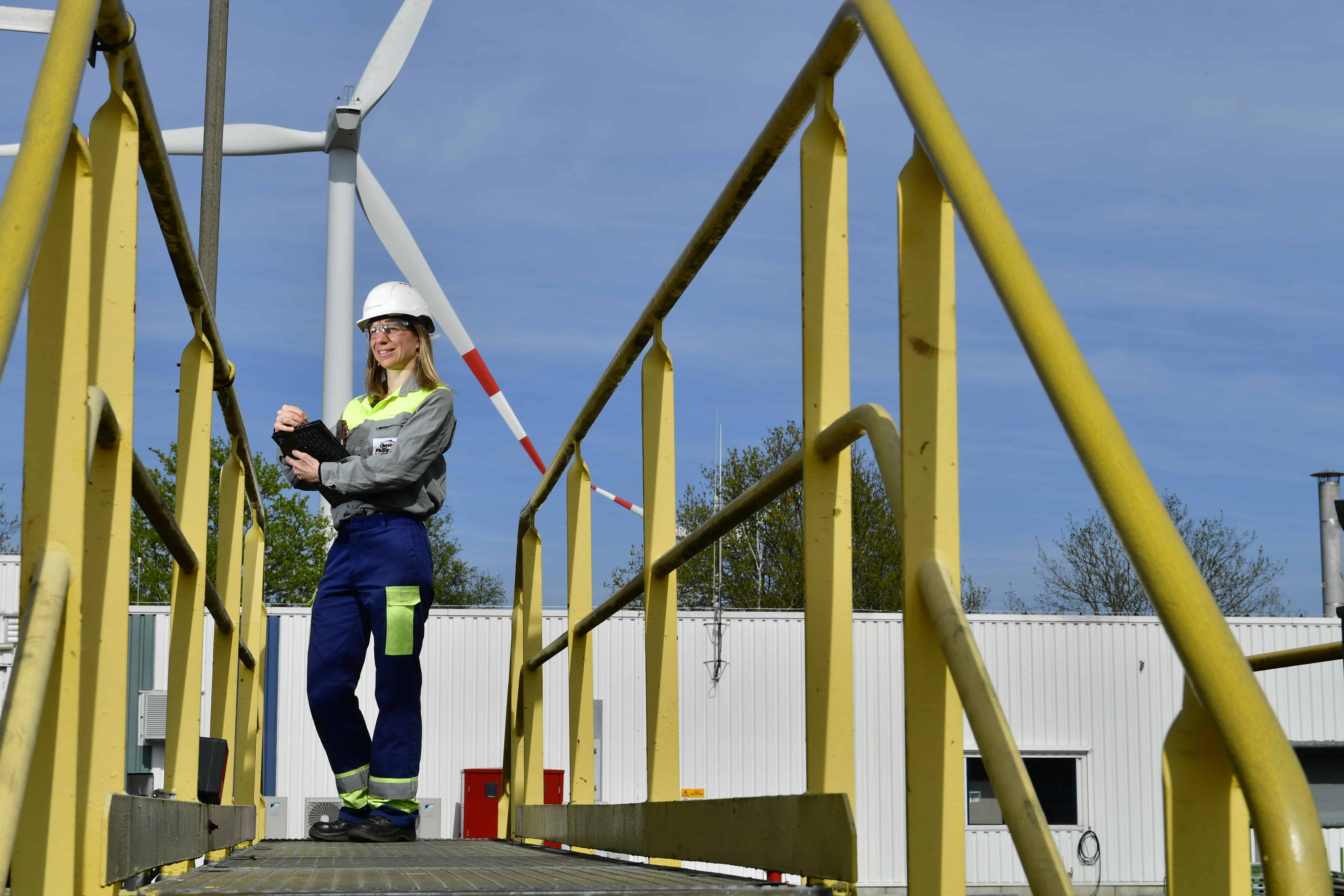 CPChem Employee in Beringen with Safety Gear and  Awind Turbine in the Background