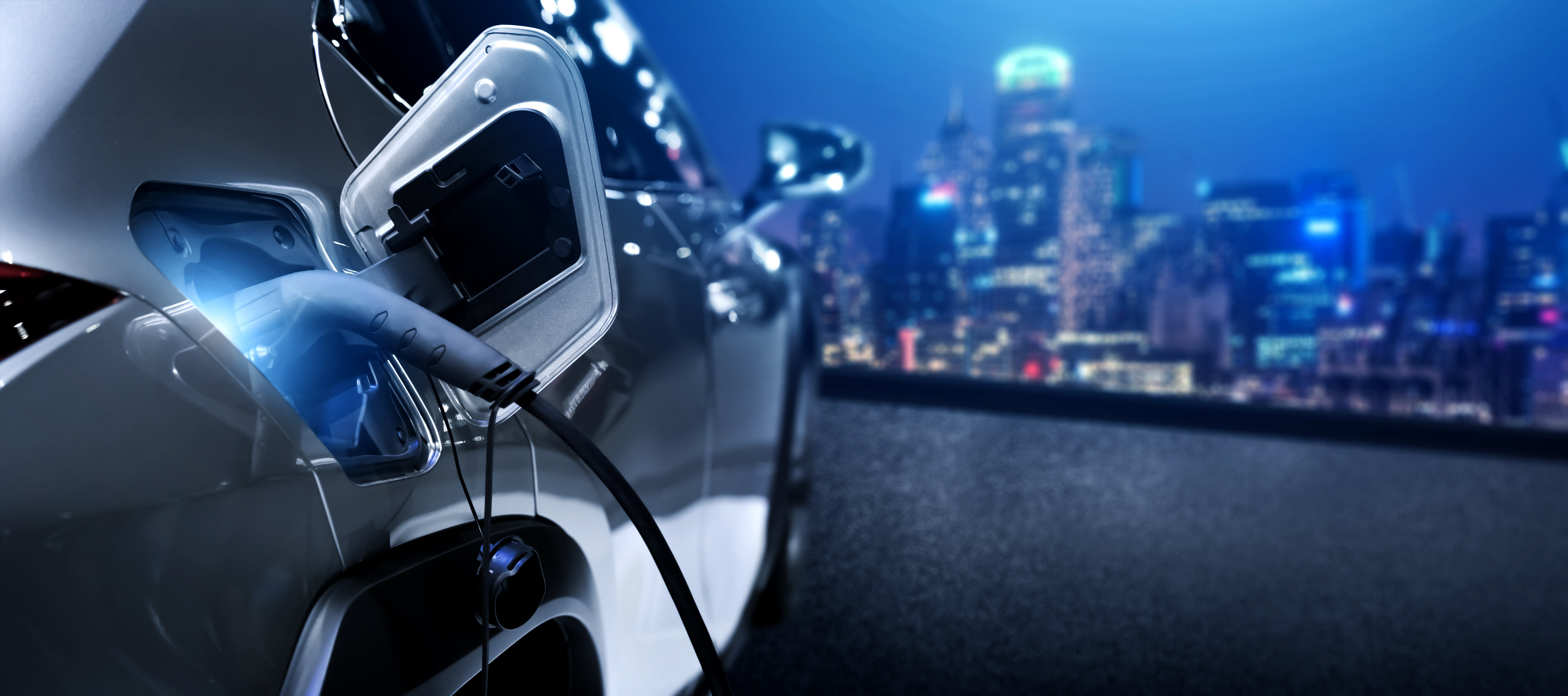 EV Charging at night with city in the background