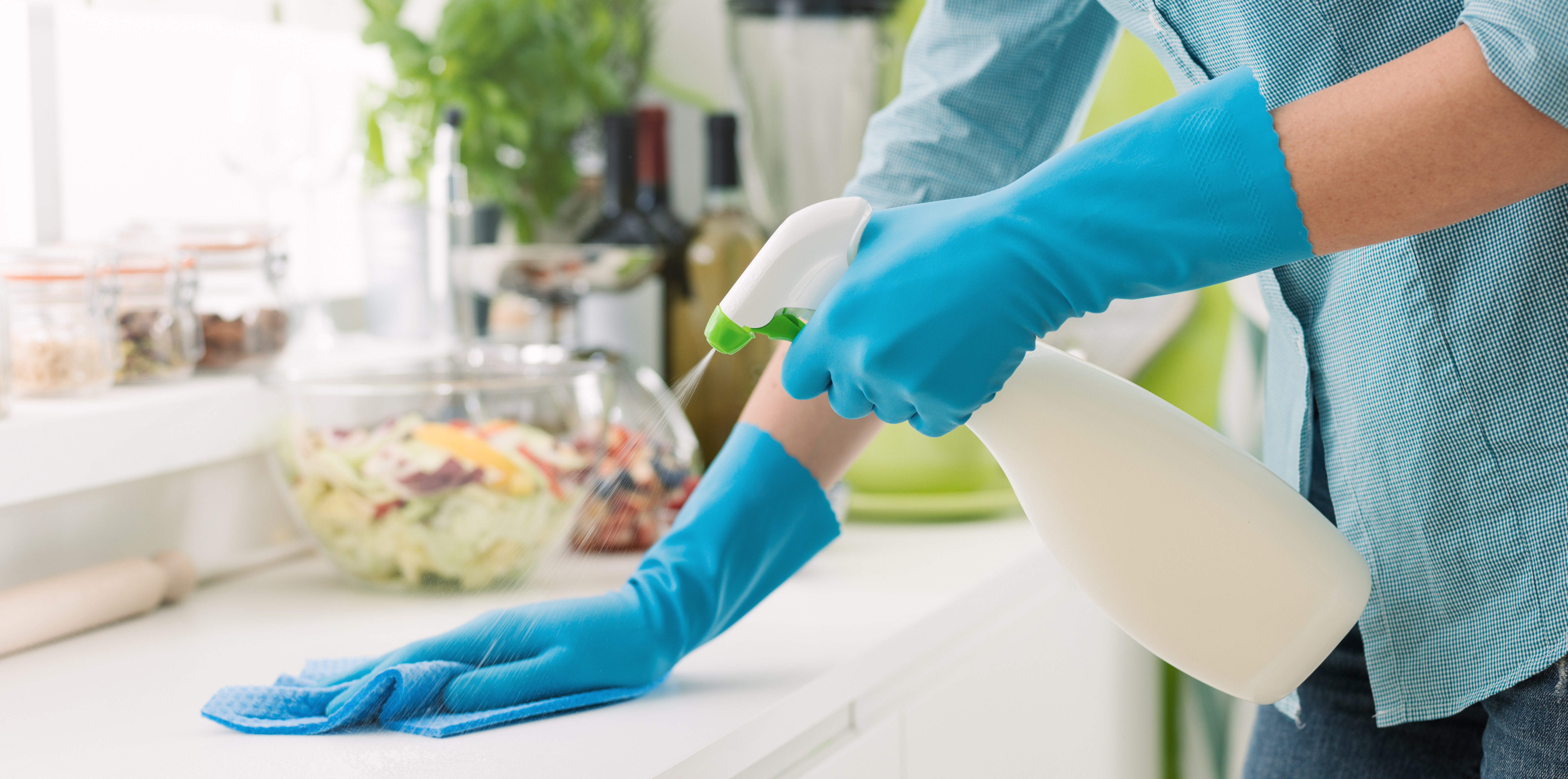 woman uses cleaning spray in a plastic bottle to clean countertops